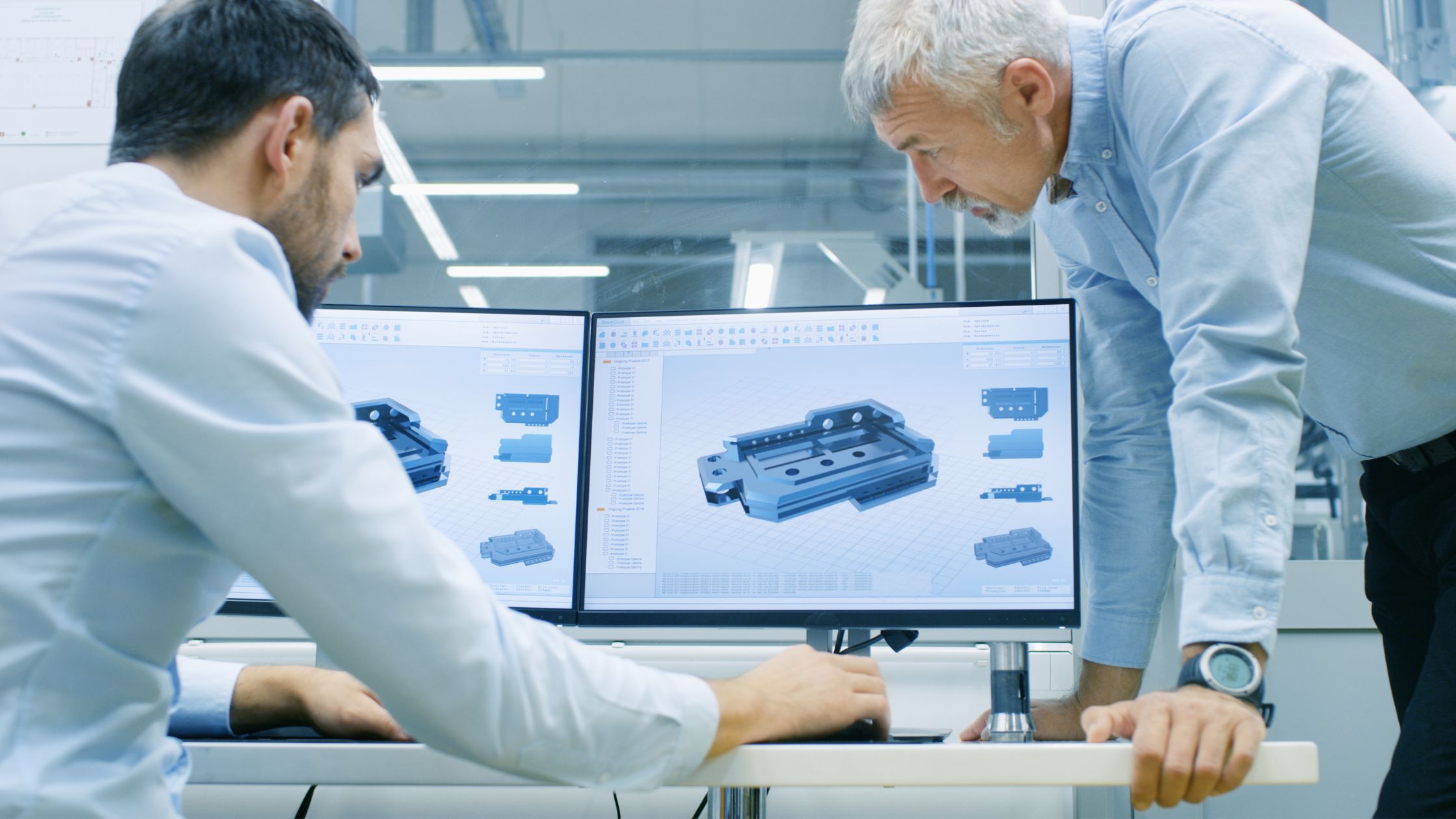 Engineers reviewing injection moulded part design on dual CAD workstation